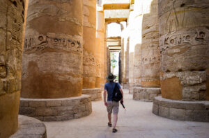 A low angle shot of a male walking between columns in  Karnak Temple in Egypt