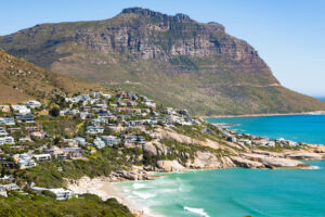 A beautiful shot of buildings on a hill at  turquoise beach in Cape Town, South Africa